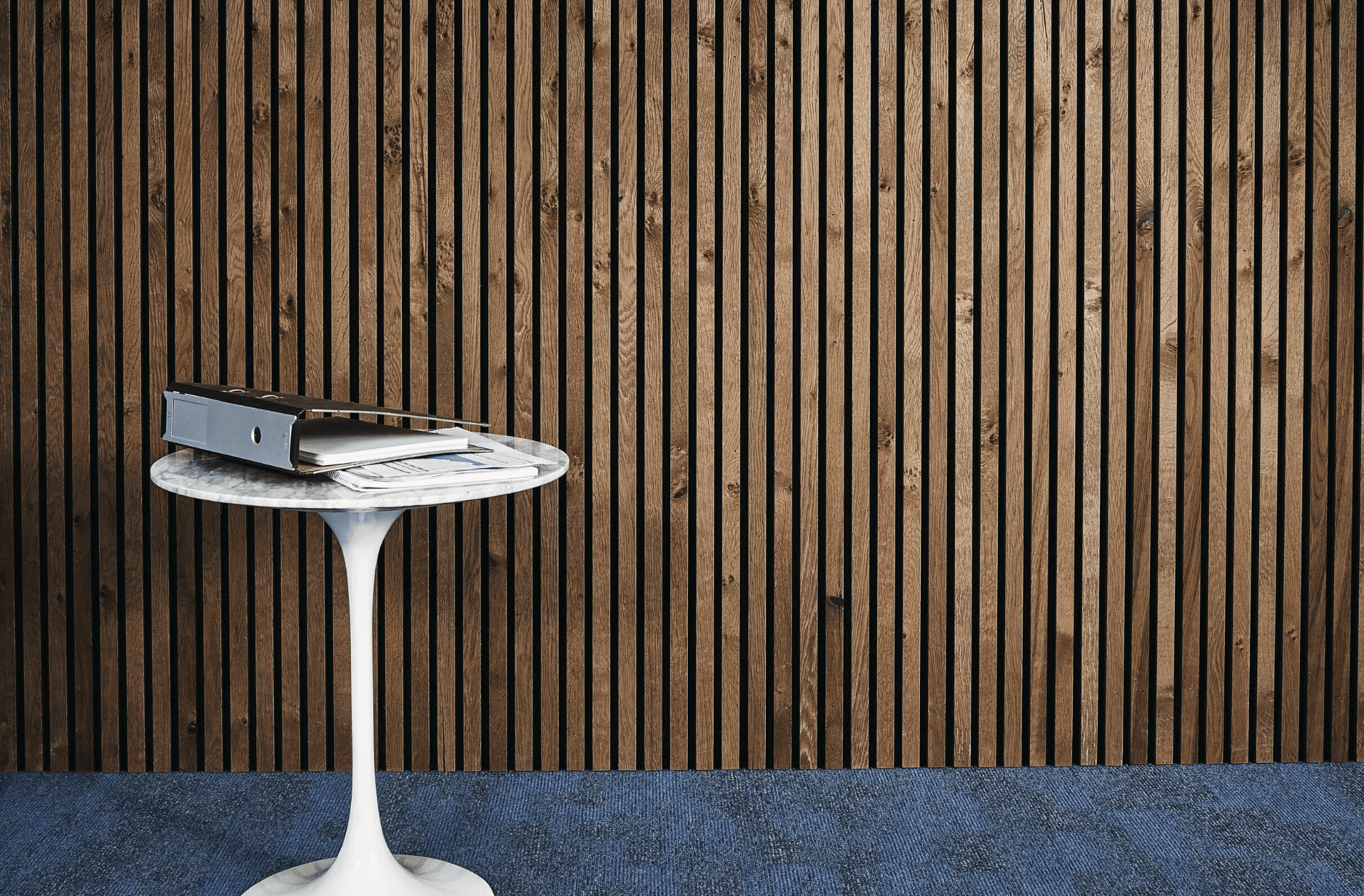 Small round table with binder and documents against a wooden slatted wall.